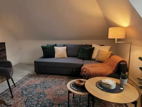 اتاق درمان تجربه پارتنر اسن در آلمان با کاناپهٔ طوسی، کوسنهای سبز و نور گرم آباژور